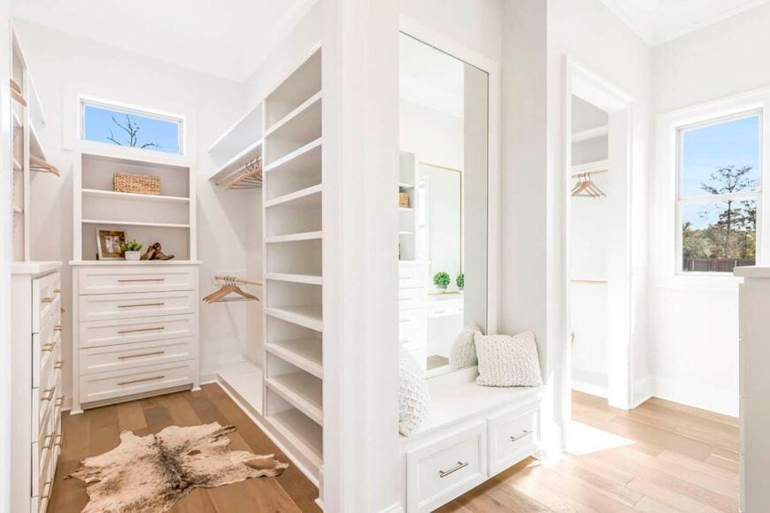 The primary walk-in closet offers plenty of storage and a built-in seat fixed against the large mirror.