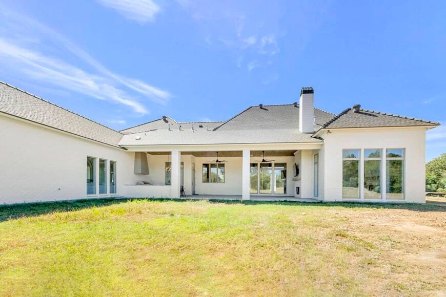 A view of the house from the backyard showcasing a covered porch that transitions to an expansive lawn.