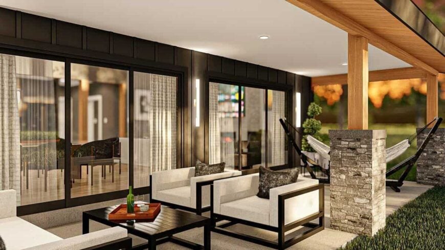 The covered patio is filled with a hammock, cushioned armchairs, and a black coffee table.