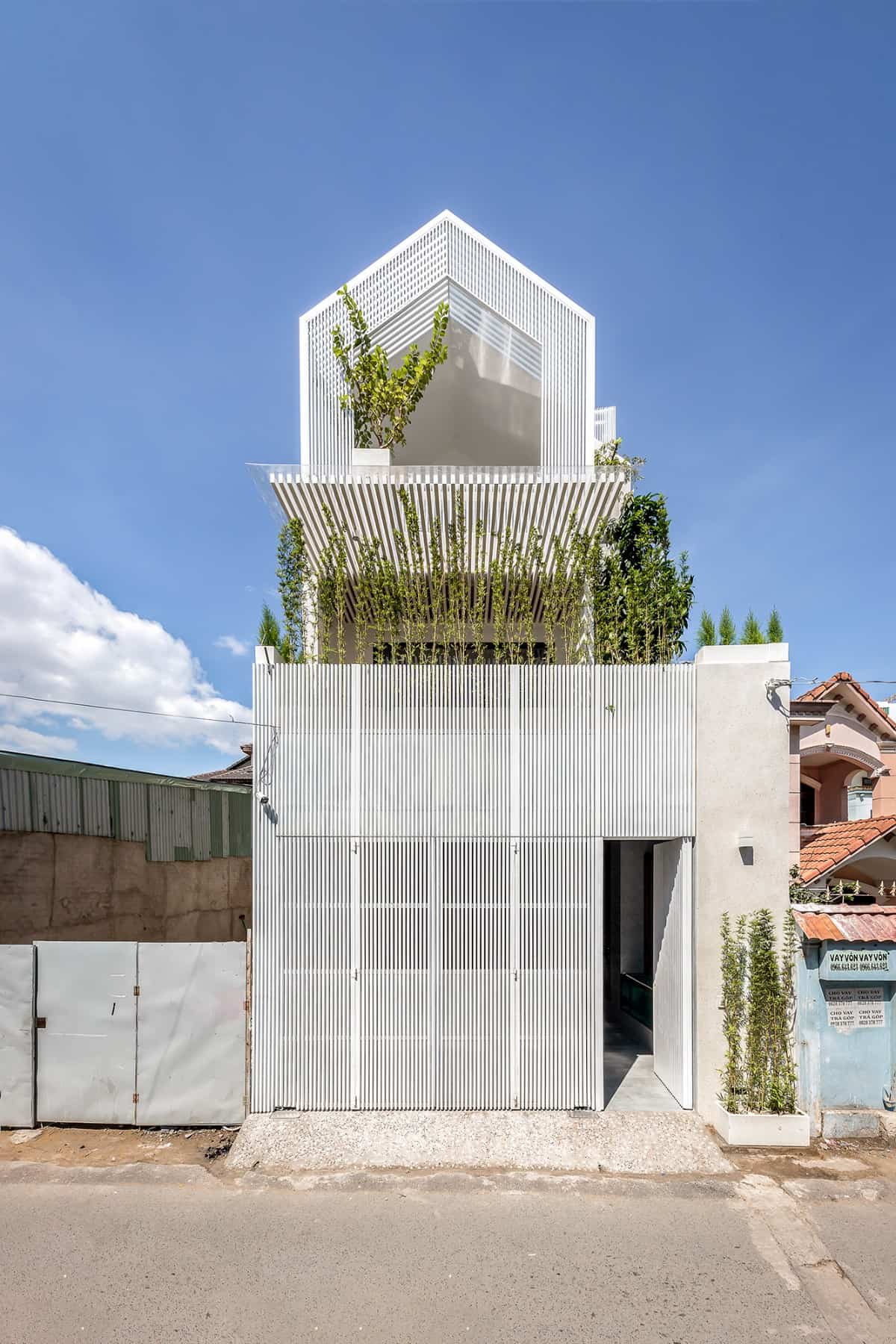 Home's facade clad in thin white wood slats. A steep gable on top adds character to the house.