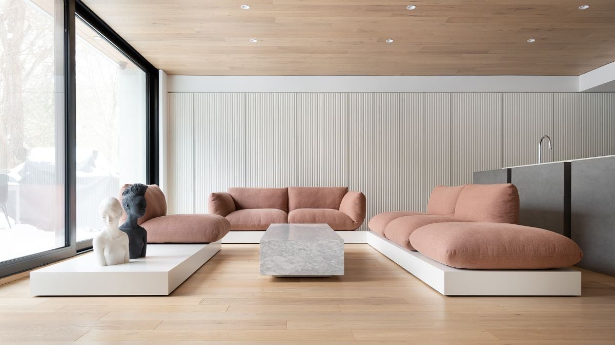  An interior shot of a spacious living room featuring a low cushion seating arrangement and an art sculpture, reminiscent of a gallery setting.