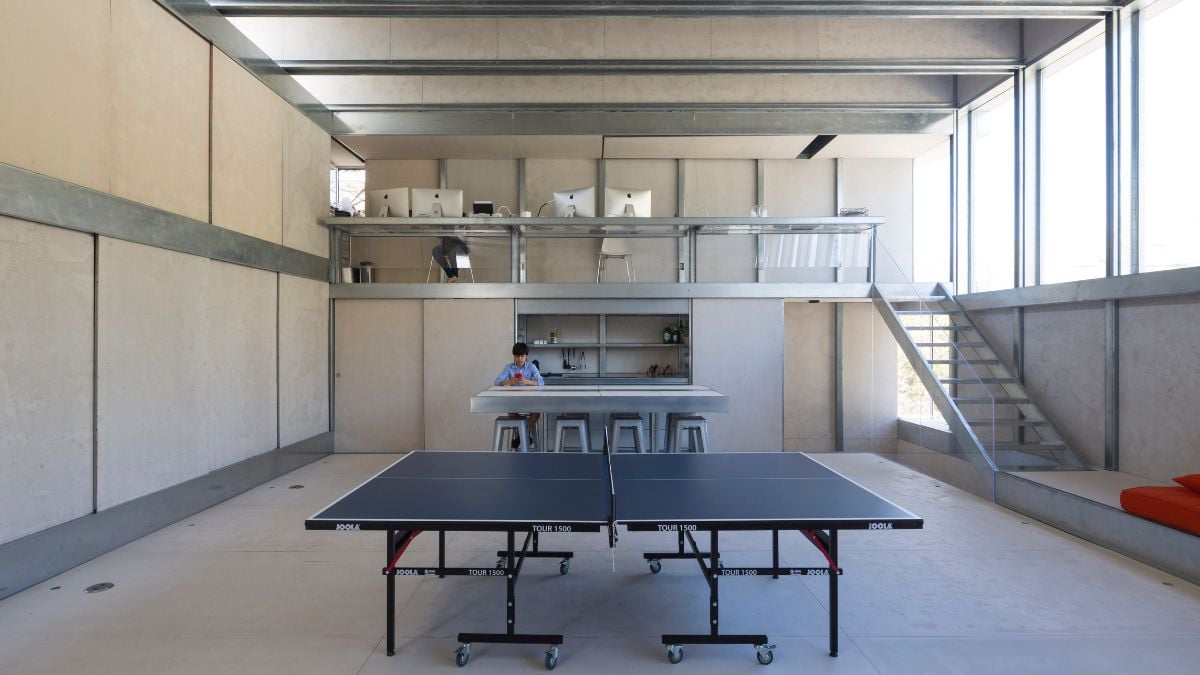 An interior shot of a spacious room that combines elements of an office and entertainment area, including a table tennis setup.