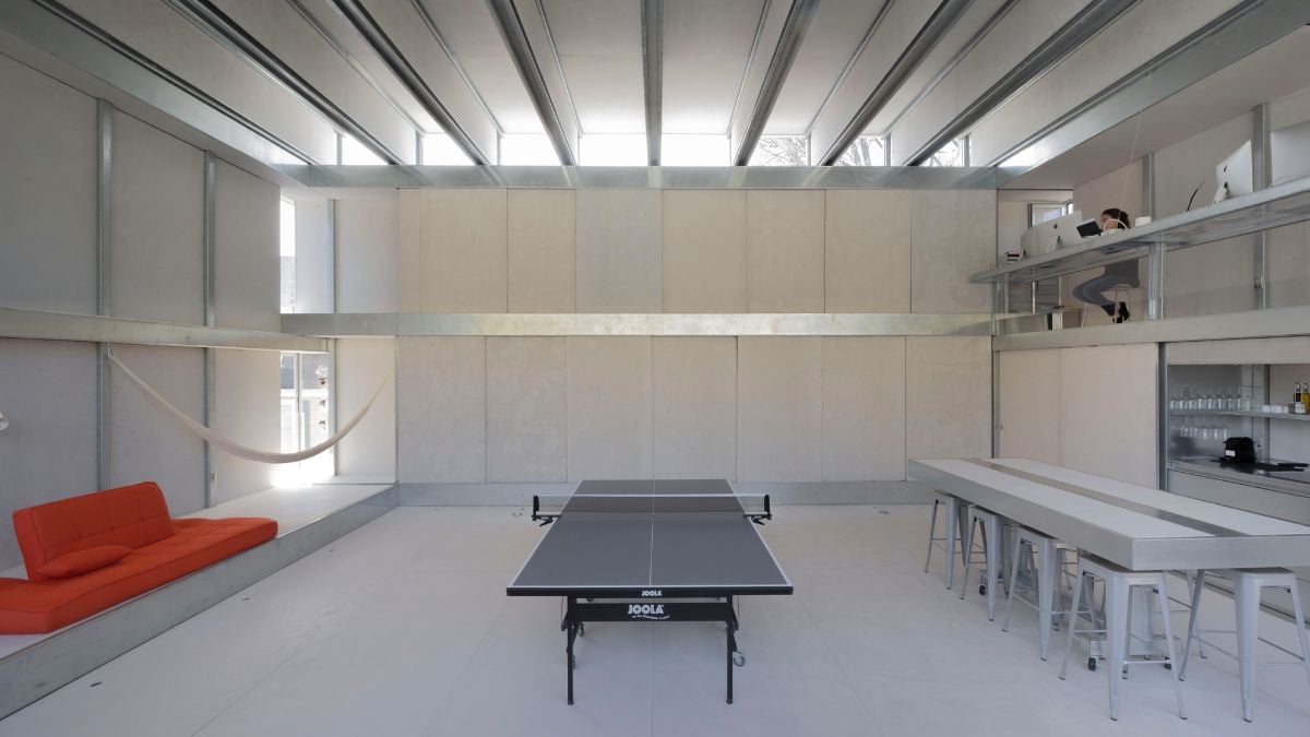 An interior shot of a spacious room that combines elements of an office and entertainment area, including a table tennis setup.