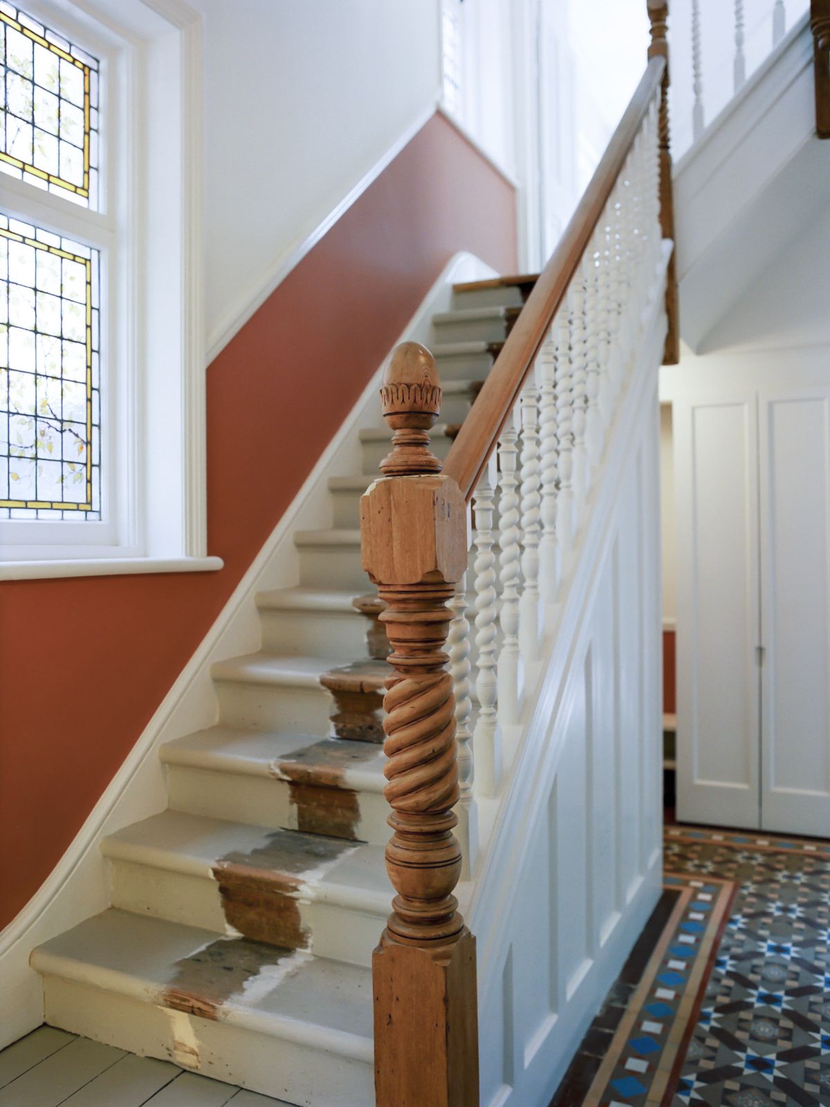 The entrance hall is beside a wooden staircase with unfinished paint giving off a rustic feeling.