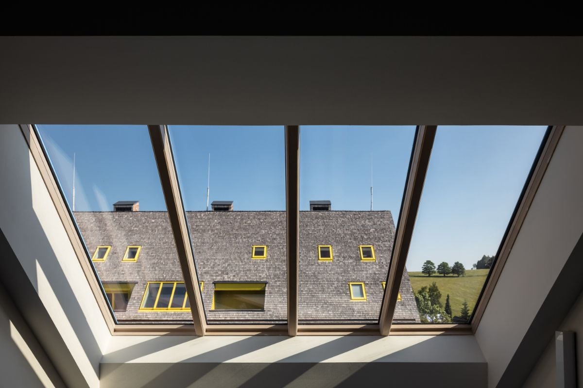 The skylight with a wooden frame overlooks the roof of the other house.