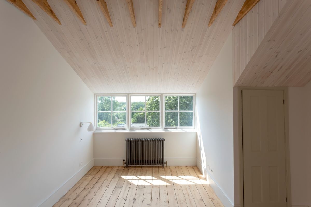 The rear bedroom has wooden floors and a ceiling, and a window that overlooks the landscape.