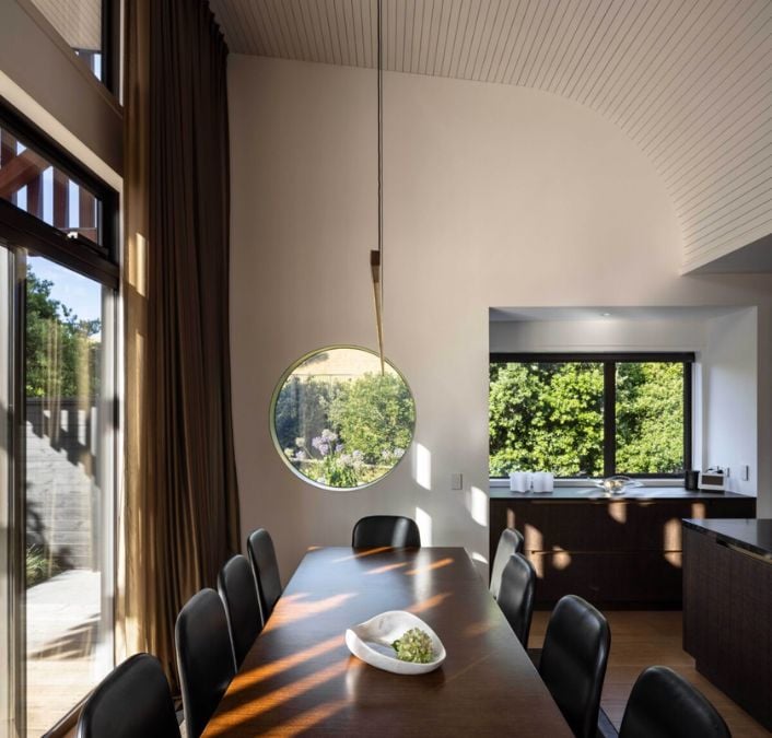 An interior photograph of the dining area, featuring the wooden dining table set and the pathway leading to the kitchen.