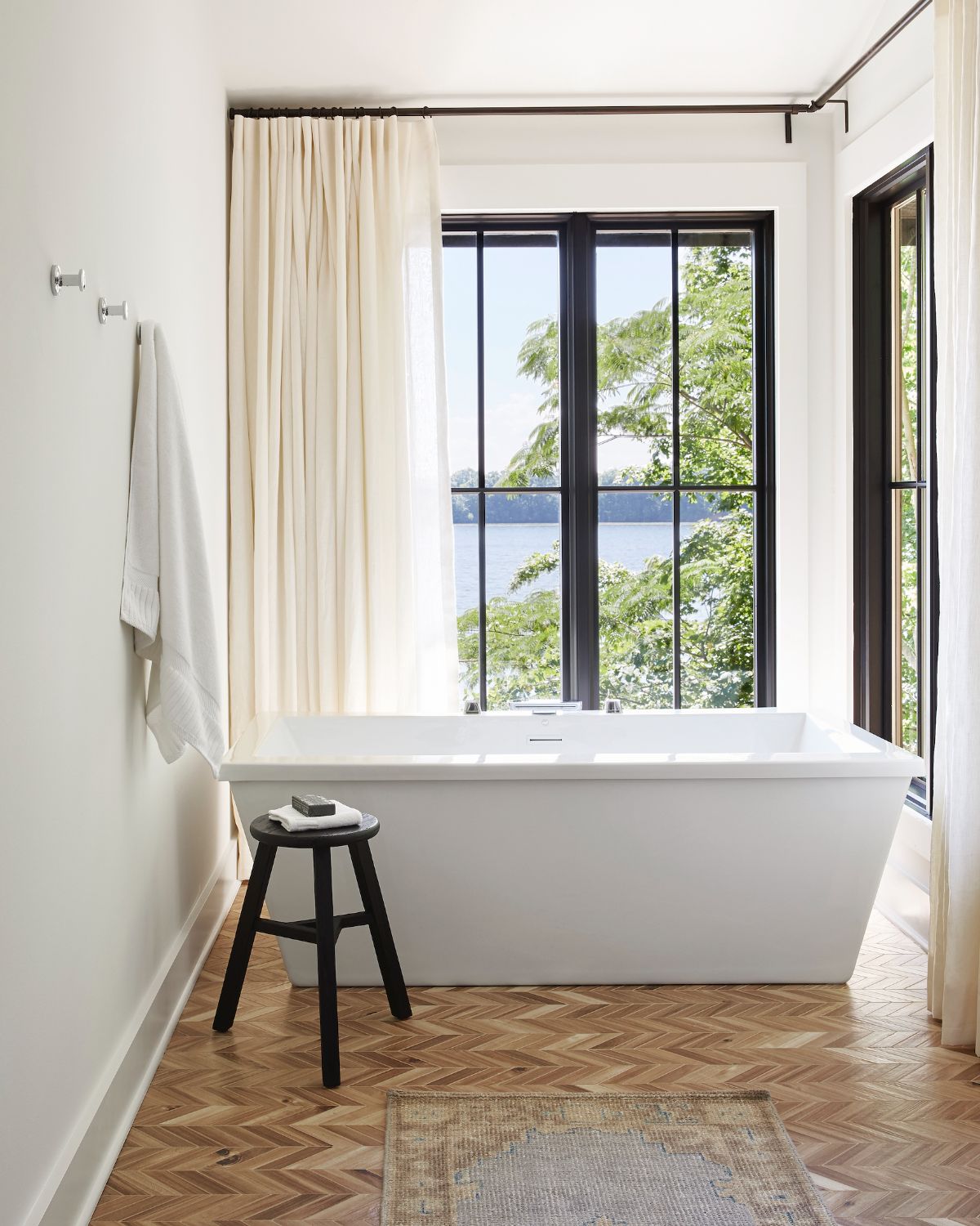 The master bathroom has a freestanding tub and curtains for privacy.