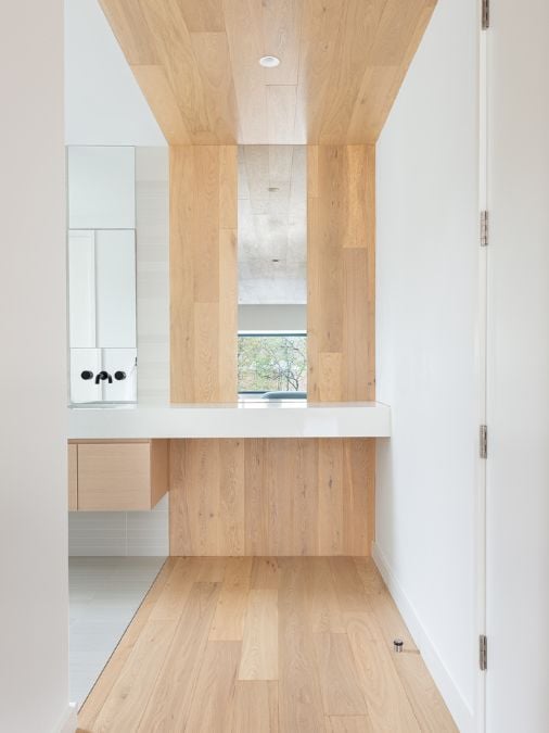 Upon entry to the bathroom, visitors are greeted with wooden flooring and an open space in the wall allowing for natural light and fresh air to flow in, creating a fresh and inviting atmosphere.