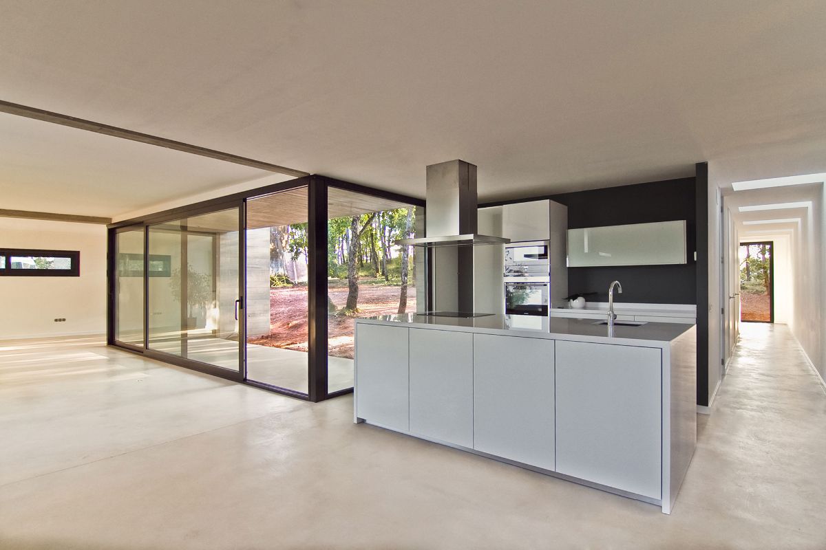 The house's interior, with concrete and iron formwork and wooden slats, as well as a floor-to-ceiling glass wall and door.