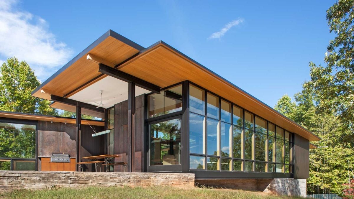 The exterior of the house is made of glass with metal frames and stone walls.
