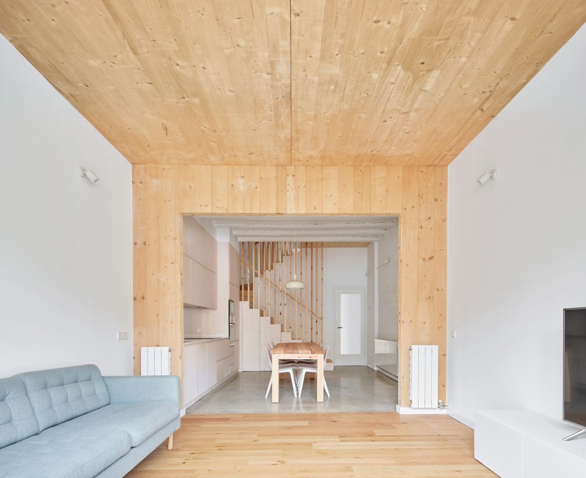 The living room has a rustic feel thanks to the presence of wood in the ceiling and floor.