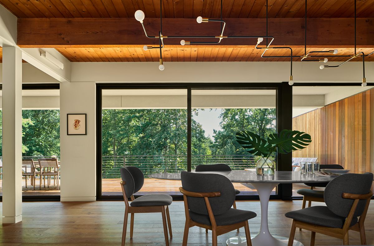 The dining area has large glass windows that provide unobstructed views of nature.
