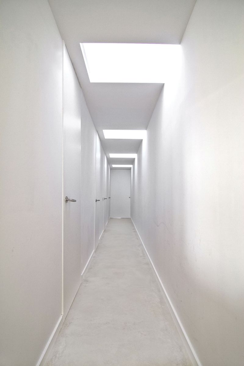An all-white, long and narrow hallway connecting the house rooms.