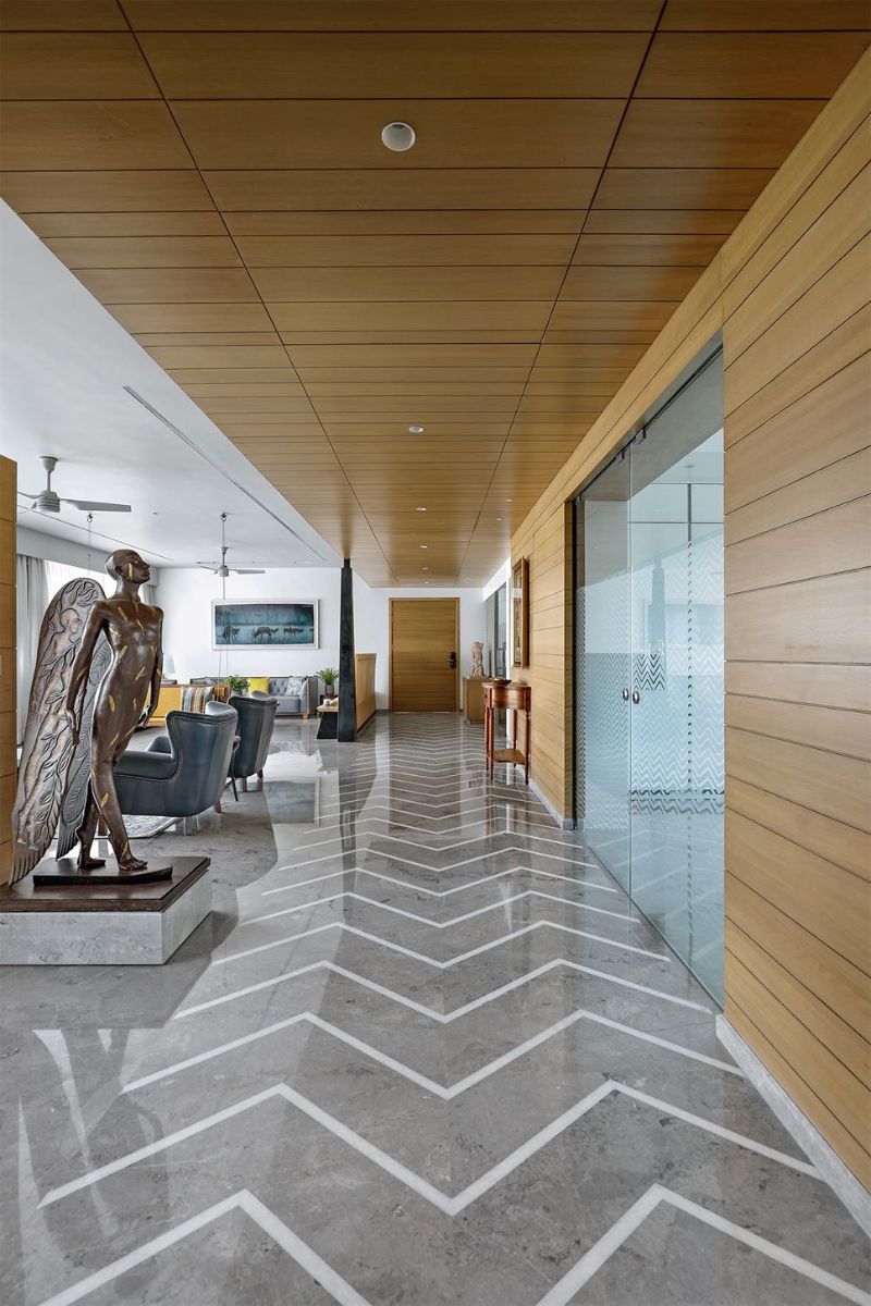 The lengthened passage standing out by the haring born pattern in white on the Italian marble flooring with veneer ceiling and bronze sculpture by Asis Das.