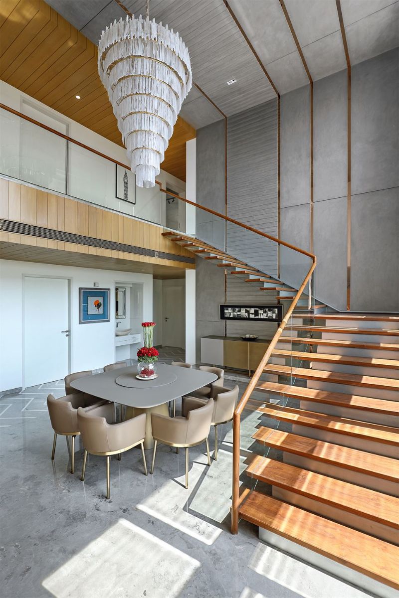 The double height dining defined from the living by the double sided TV unit and magnificent chandelier hanging from the micro concrete ceiling.