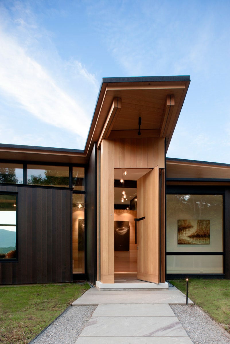 The entrance has a concrete walkway, and the presence of wood gives off a welcoming atmosphere.