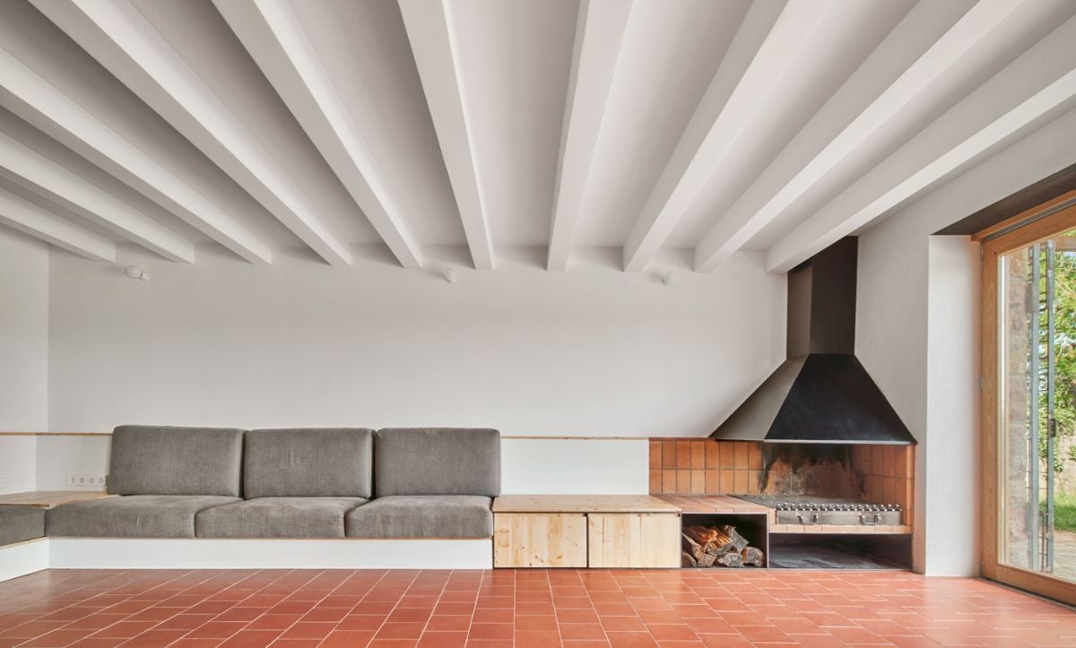 The living room has tile flooring and a sofa next to an open fireplace.