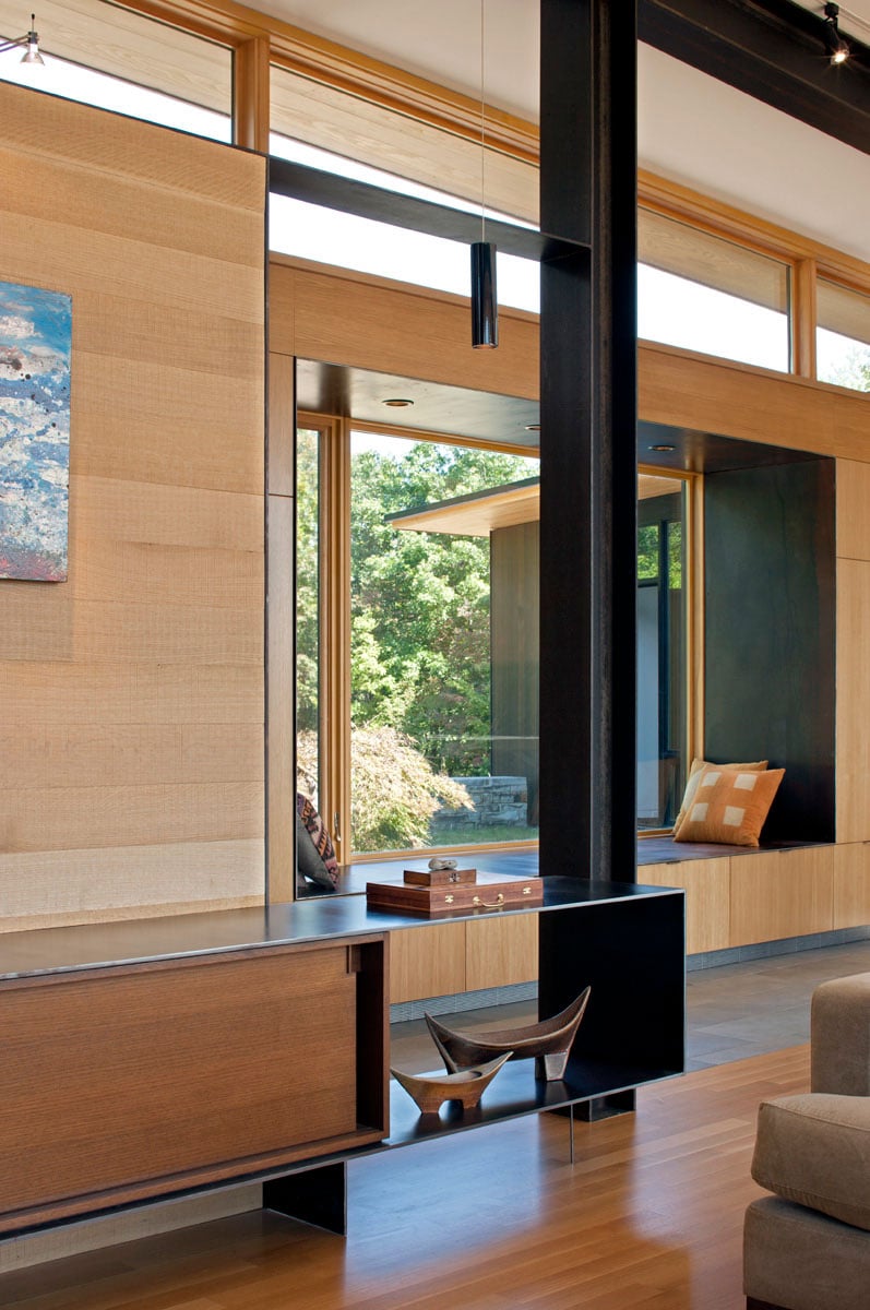 The living room features a window seat overlooking the garden through a glass window.