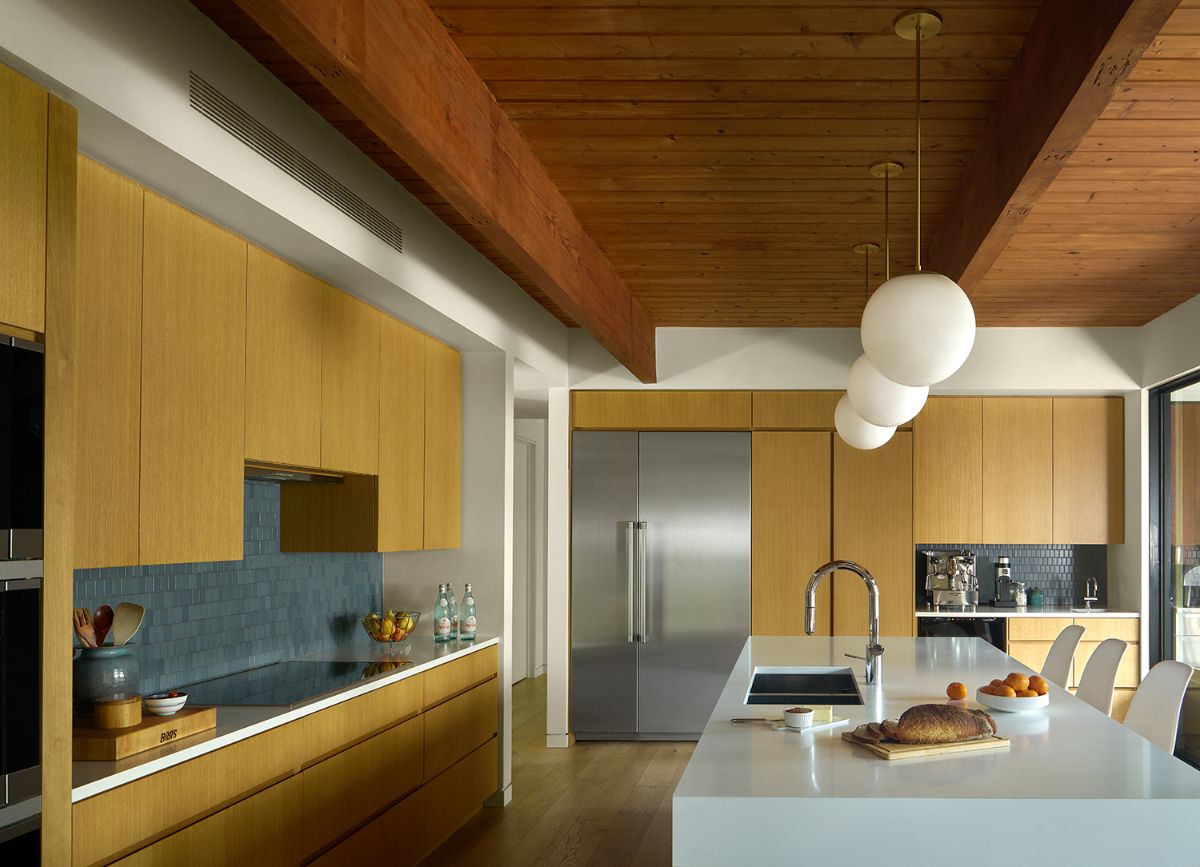 A kitchen with custom cabinetry made of oak wood with quartz countertops.