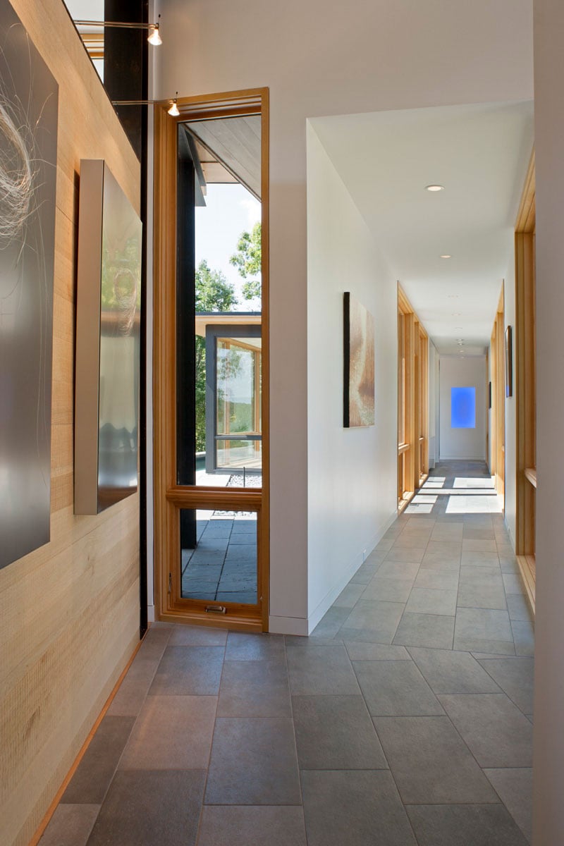 The hallway with tile flooring leads to the outdoors and bedrooms.