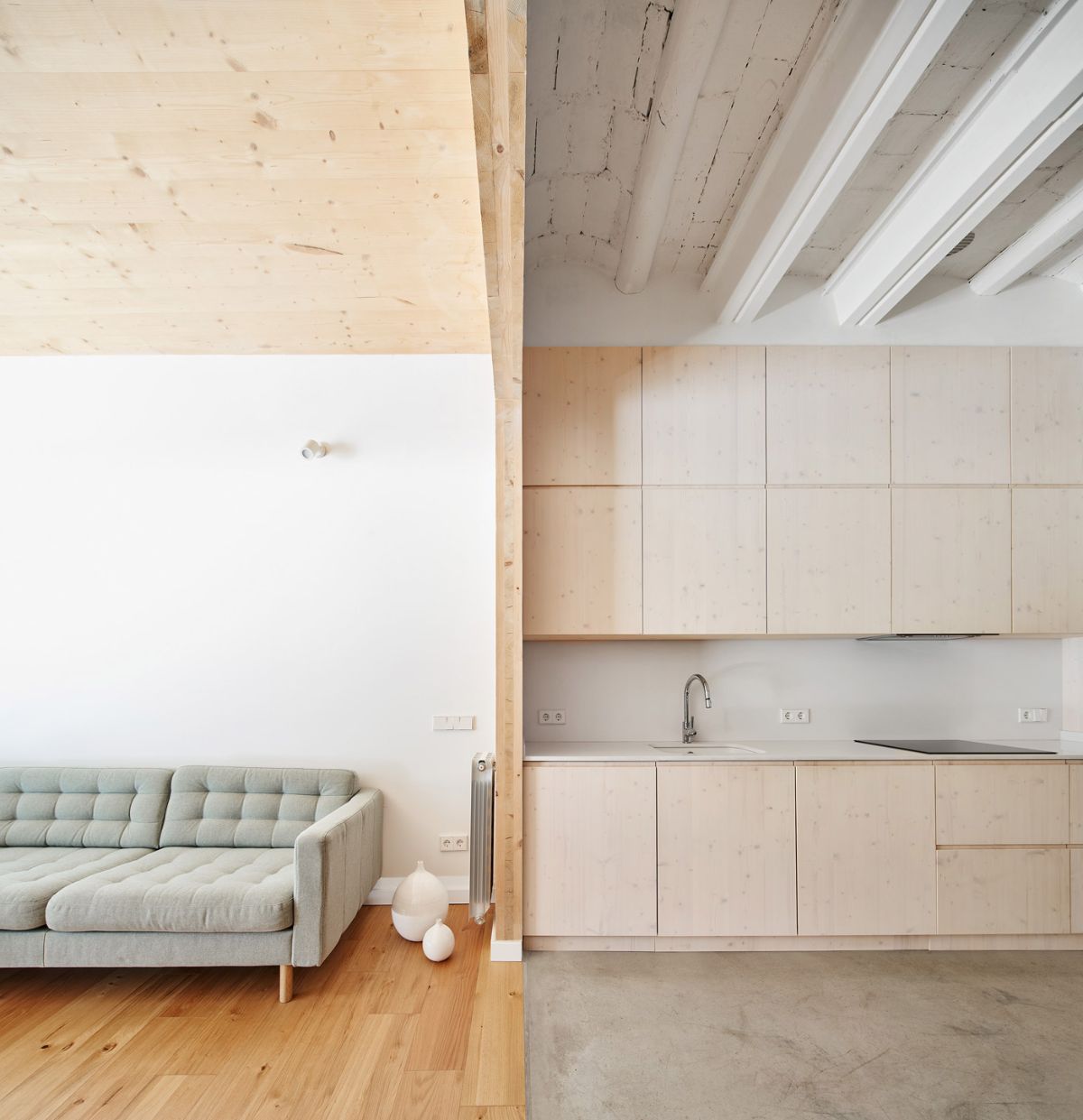 The wooden floor and ceiling separate the living room from the kitchen and dining area.