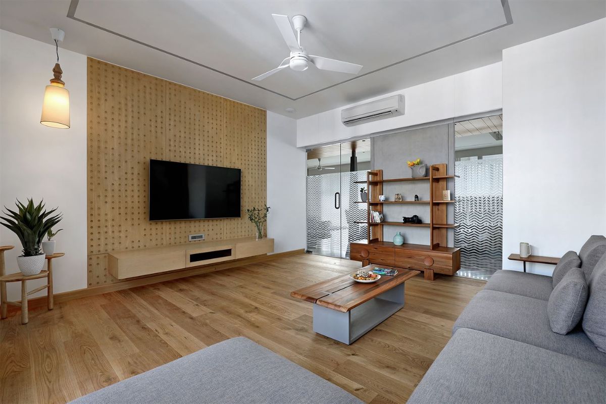 TV room has wooden flooring giving a subtle vibe with the greys and line patterned fabric on walls for acoustic purpose.