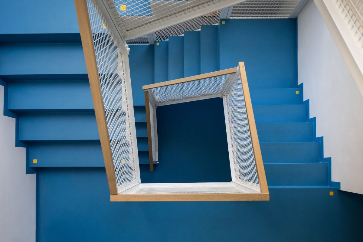 The staircase is painted with vibrant blue color leading to the upper floors.