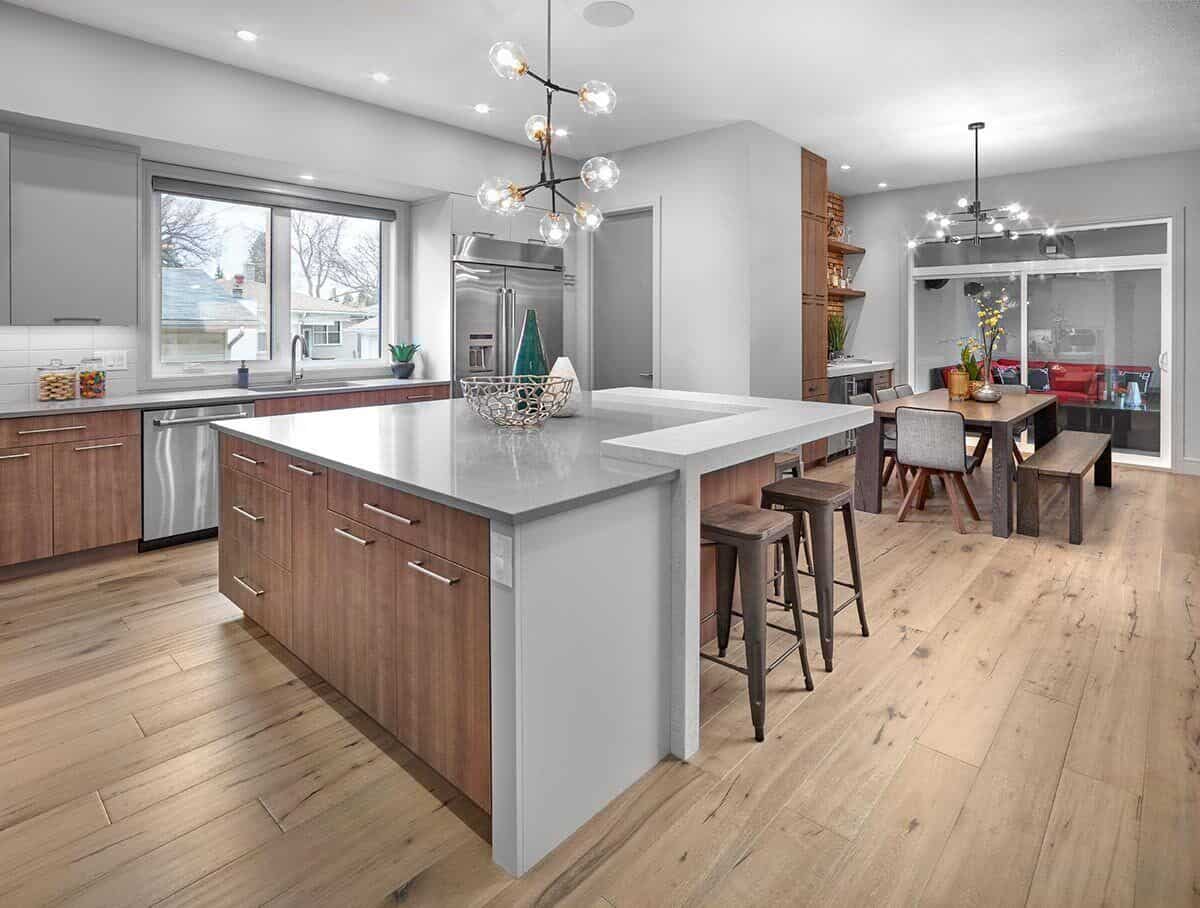 The kitchen has stainless steel appliances, wooden cabinets, an immense center island, and an adjoining dining room.