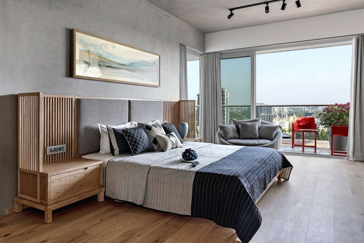 A bedroom with micro concrete walls with an exposed lights and the red seats utilized in the balcony.