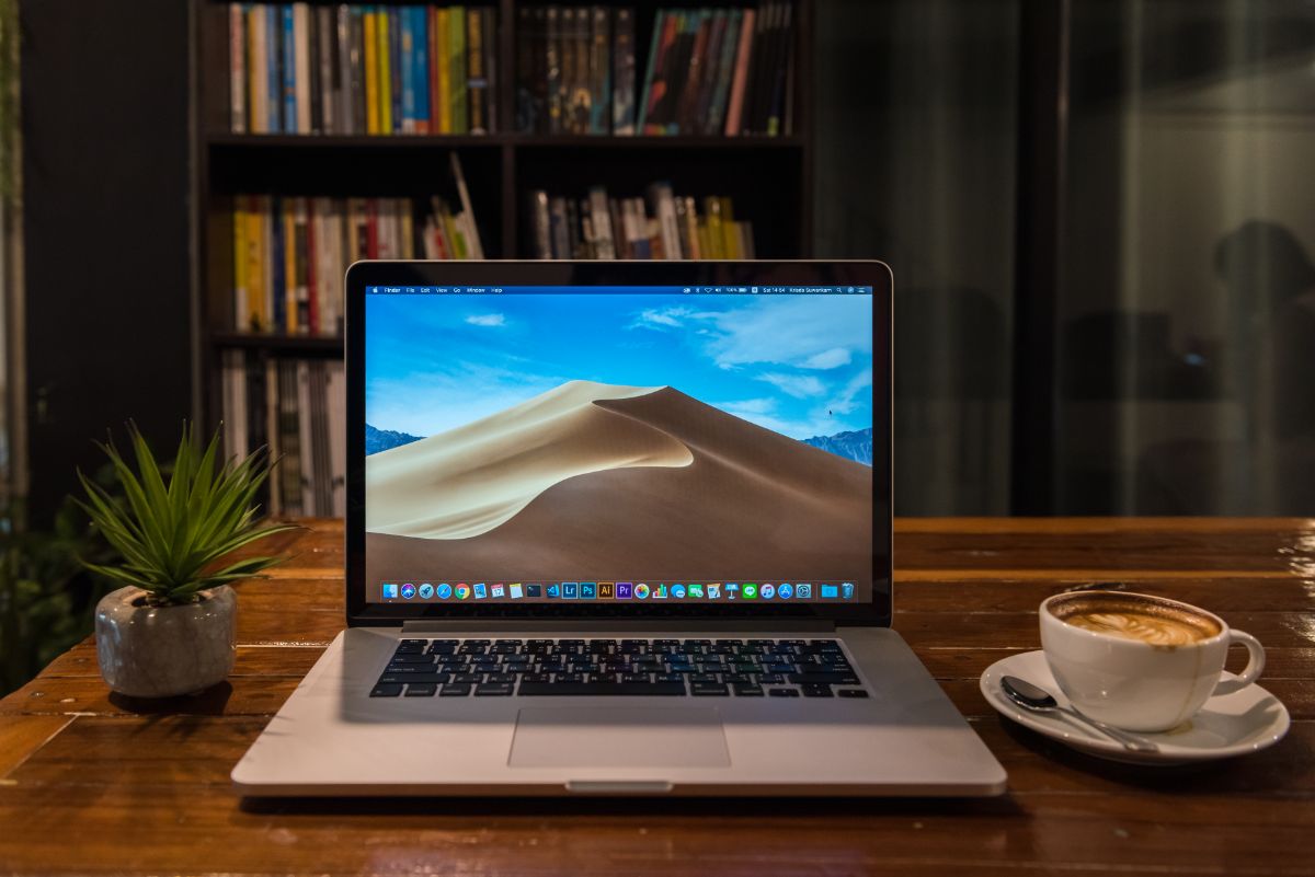 A MacBook pro on a table and a cup of coffee.