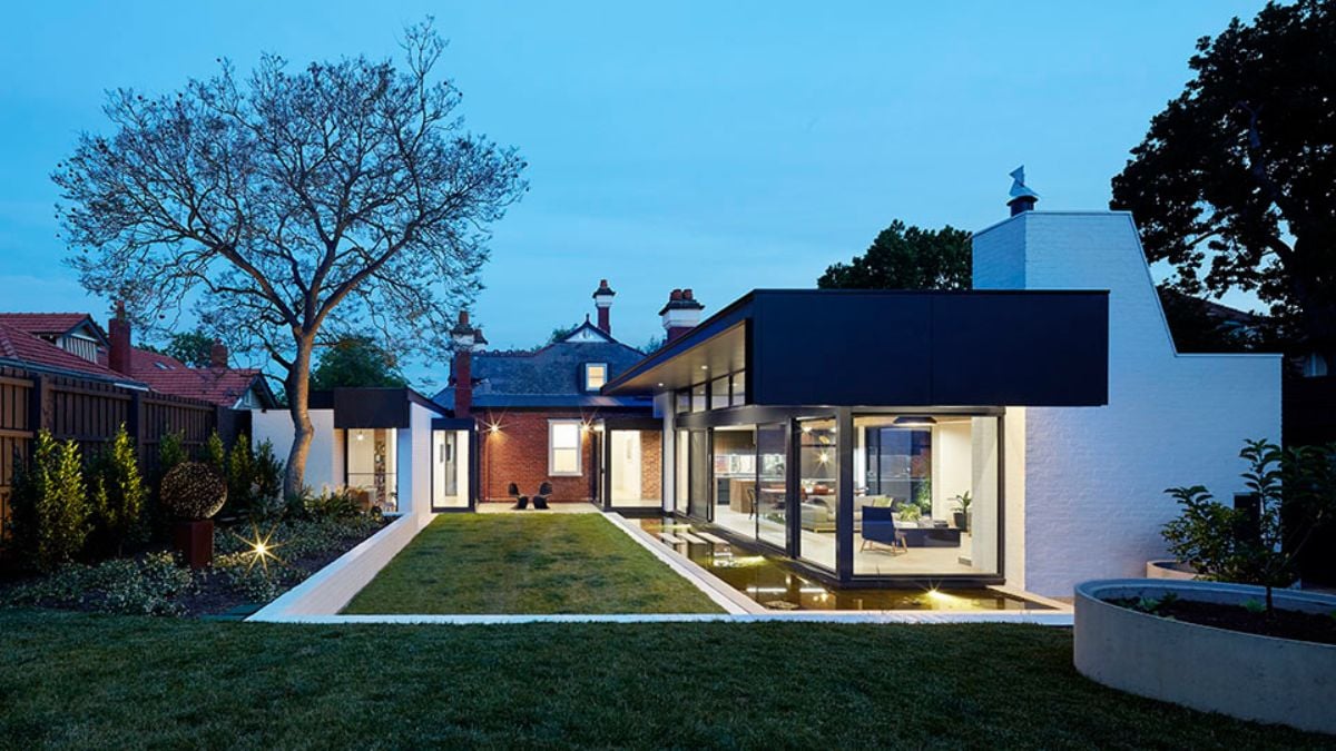 The photo depicts a twilight view of the exterior of the Pond House, highlighting the surrounding landscape and the spacious outdoor area surrounding the building.