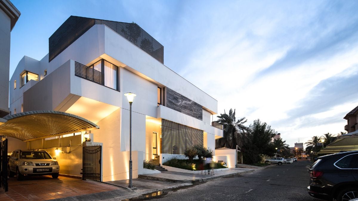Exterior shot of the house with a white and brown color scheme and a small car park beside it.