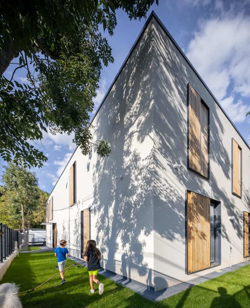 The home's exterior showcases textured white plaster and sliding wood shutters bordered by steel frames.