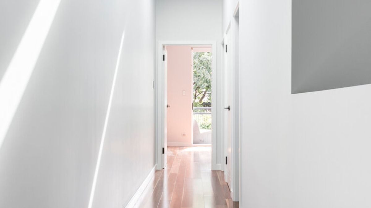 The narrow hallway is taking advantage of a wide side access and skylights to flood the space with natural light.