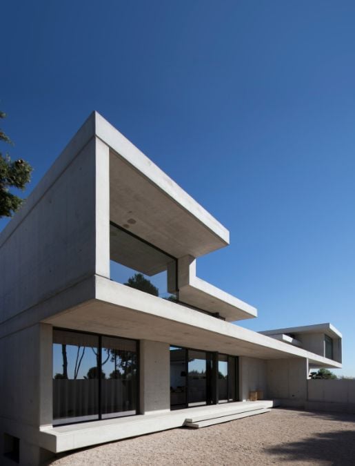 A low-angle shot emphasizing the contemporary concrete architectural design of the house.