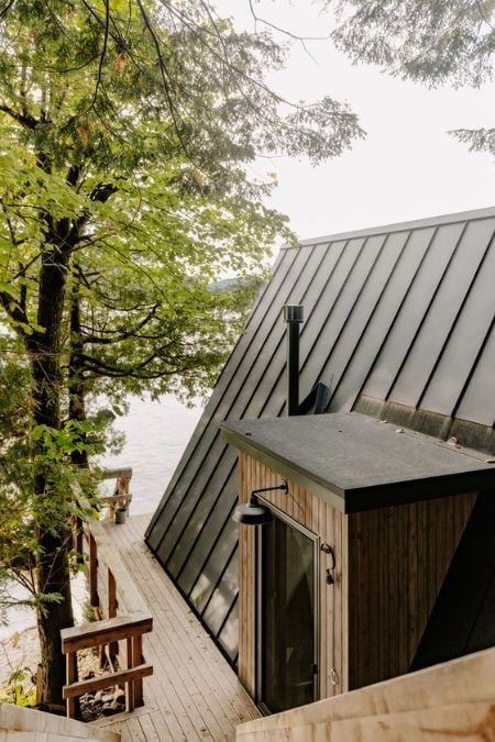 A picture displaying the metal roofing design of the house and a walkway along its side, with a small doorway leading to the interior deck.