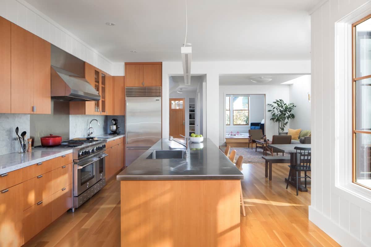 The kitchen includes stainless steel appliances, a center island, and views of the dining and living rooms.