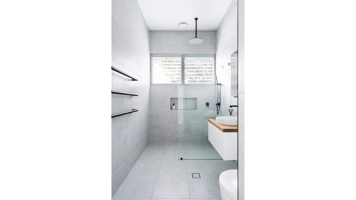 The modern bathroom is oriented north to capture direct natural light and distant tree views.