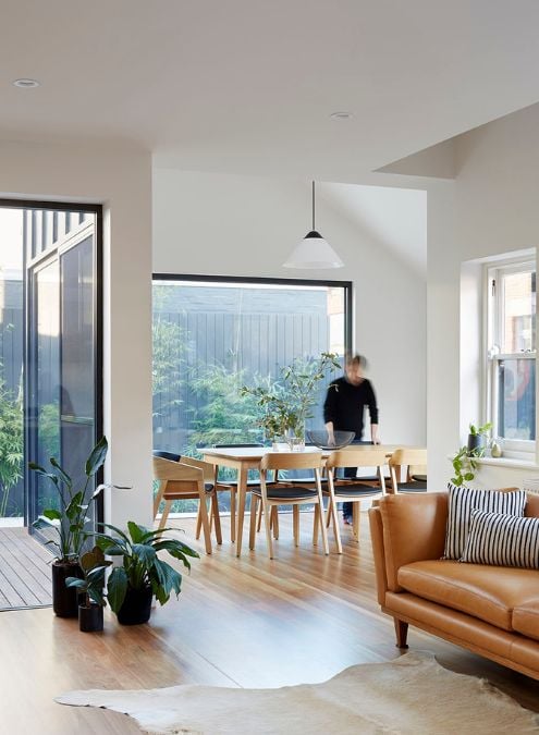 This photograph features the seamless integration of the living and dining spaces in the house, providing a view of the outdoor area through the glass walls.