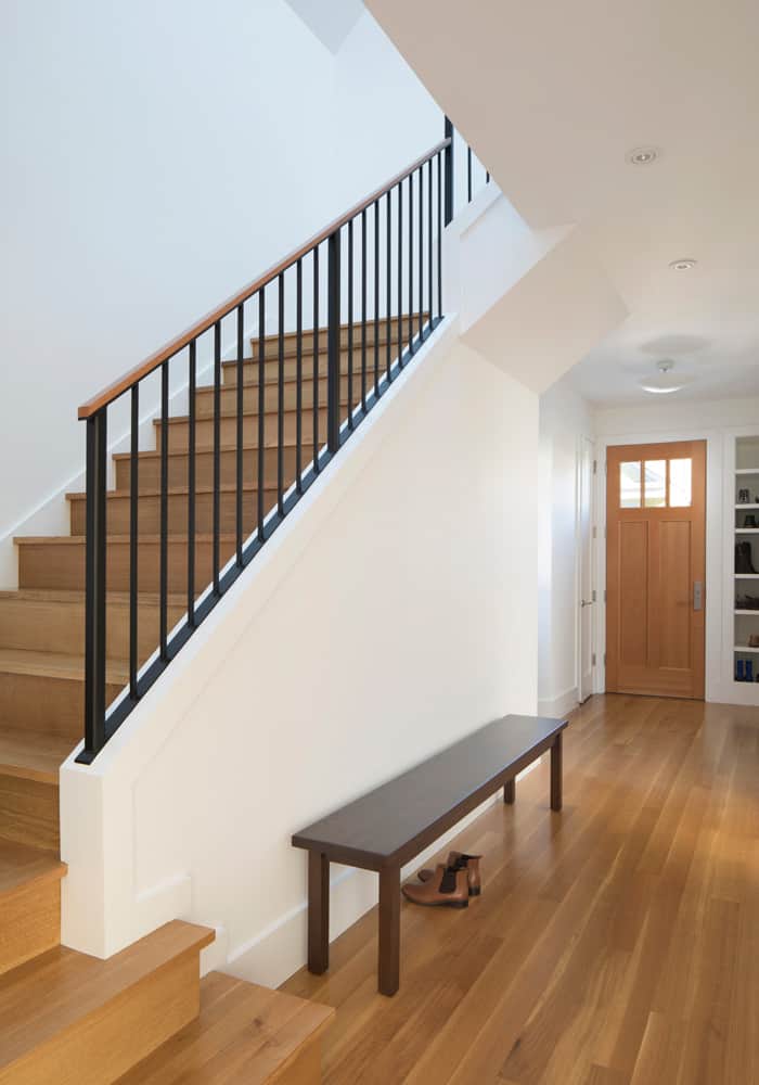 The foyer has a dark wood bench and a wooden staircase that leads to the upstairs bedrooms.