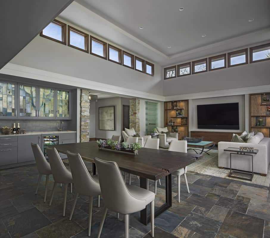 The dining area features a rustic wooden table paired with leather upholstered chairs.