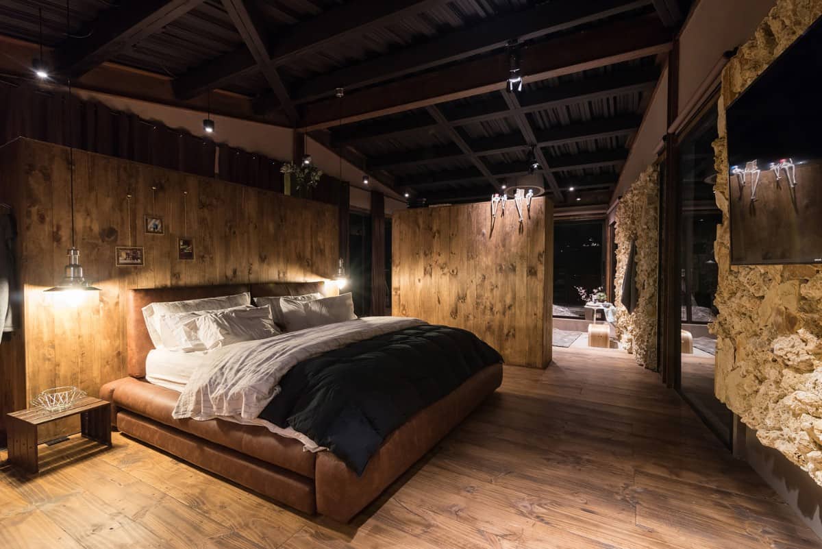The stone and wood-paneled walls continue to the bedroom to maintain cohesiveness.