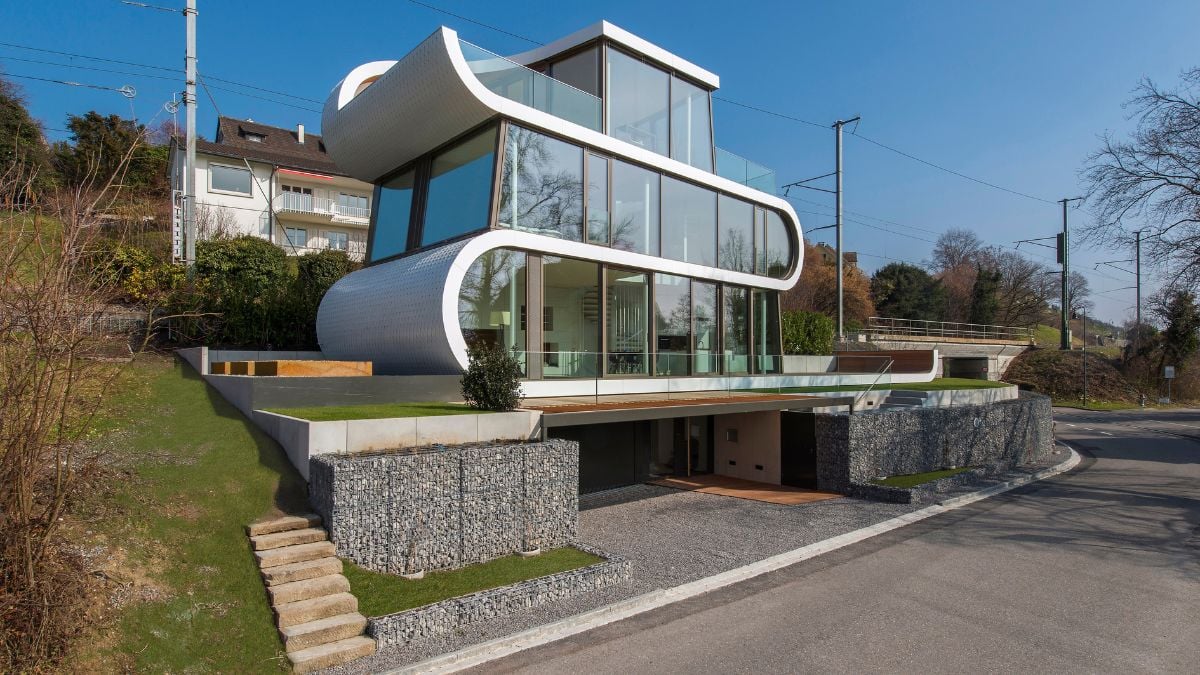 The home has tall glass walls and a white façade that wraps around the entire structure.