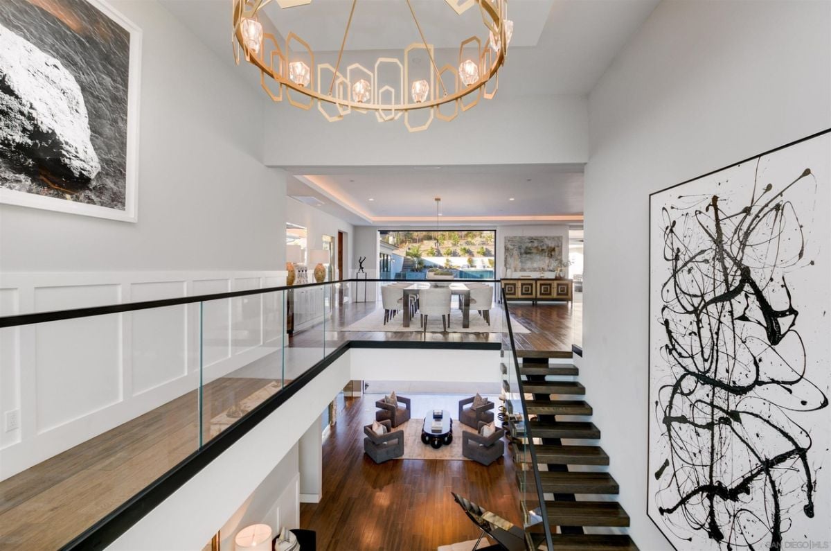 The beautiful staircase leads to the upper floors and is lit by a luxurious ceiling lamp.