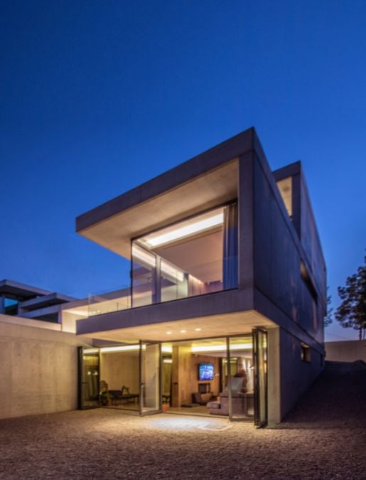 A side low-angle exterior view of the house during nighttime when the lighting is typically subdued.
