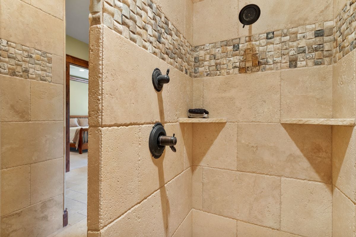 The shower room features concrete walls and stone tile giving off a classic feel.