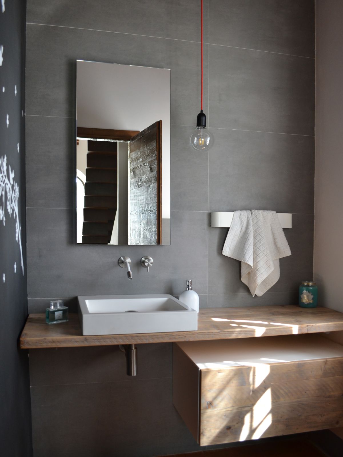 The bathroom features a wooden counter, an over-the-counter sink, and a floating drawer.