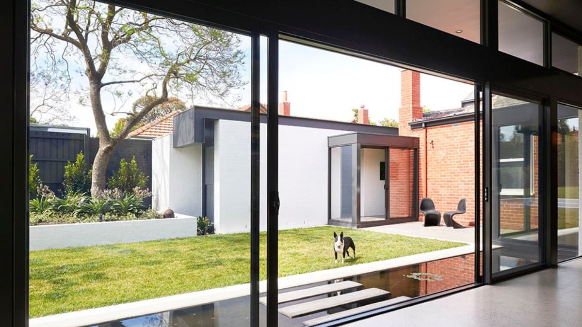 The living room has large glass panels that allow you to see the spacious outdoor area from inside.