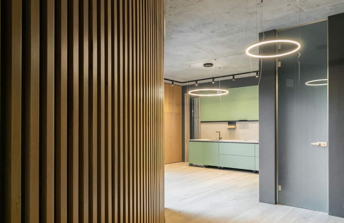 A curved hallway clad in wood slats opens to a spacious kitchen.